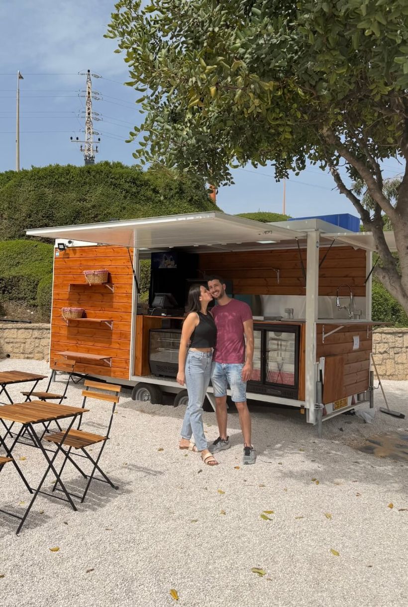 זוג מצטלם מחייך מול עגלת הקפה בנחל